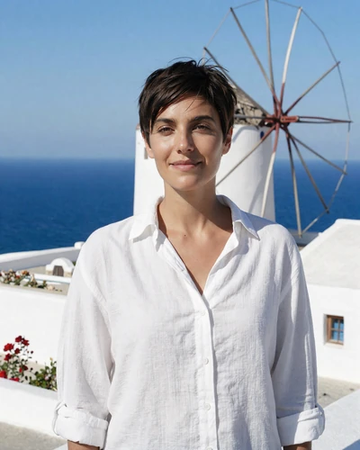 Greek woman Maria in front of whitewashed Mykonos windmills with Aegean Sea