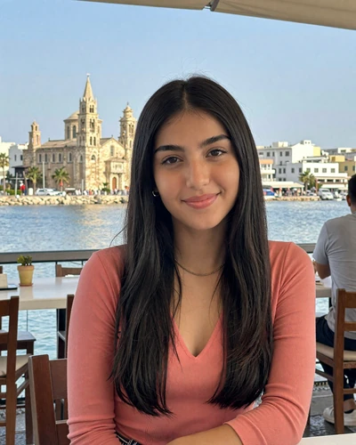 Cypriot woman Elena at a seaside cafe in Larnaca Cyprus with historic architecture behind