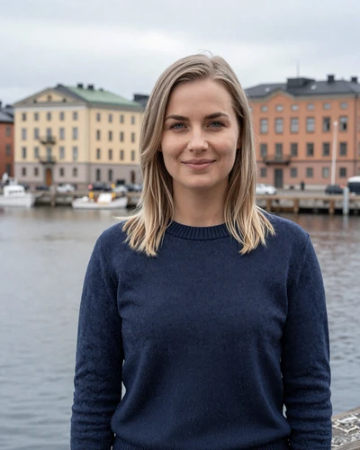 Finnish woman Aino at Helsinki waterfront wearing navy sweater with harbor behind