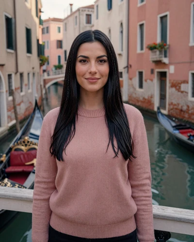 Italian woman Alessandra on a canal bridge in Venice with gondolas behind