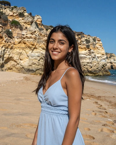 Portuguese woman Beatriz on a golden Algarve beach with limestone cliffs behind