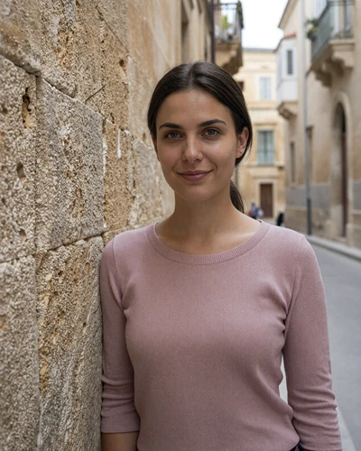 Maltese woman Roberta beside medieval limestone walls in the silent city of Mdina Malta