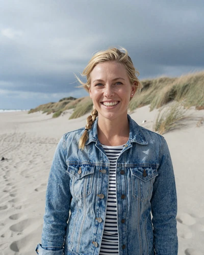 Danish woman Clara laughing on a North Sea beach near Esbjerg with dunes behind