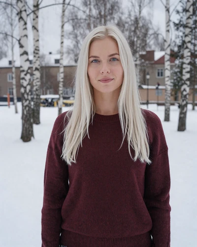Finnish woman Venla in a snowy park in Oulu wearing burgundy sweater