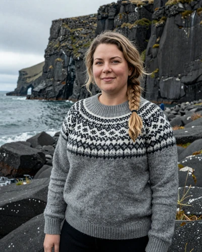 Icelandic woman Birna wearing a lopapeysa sweater on a dramatic coastline near Hafnarfjordur
