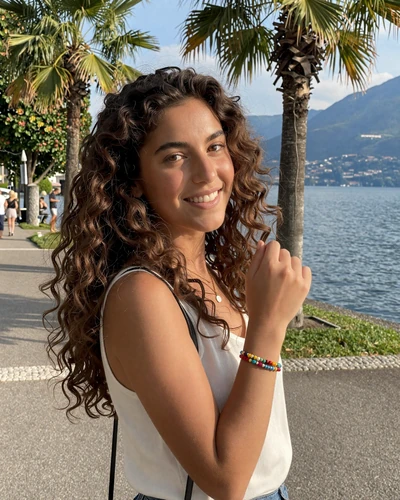 Swiss-Italian woman Giulia on the lakeside promenade in Lugano with palm trees and lake